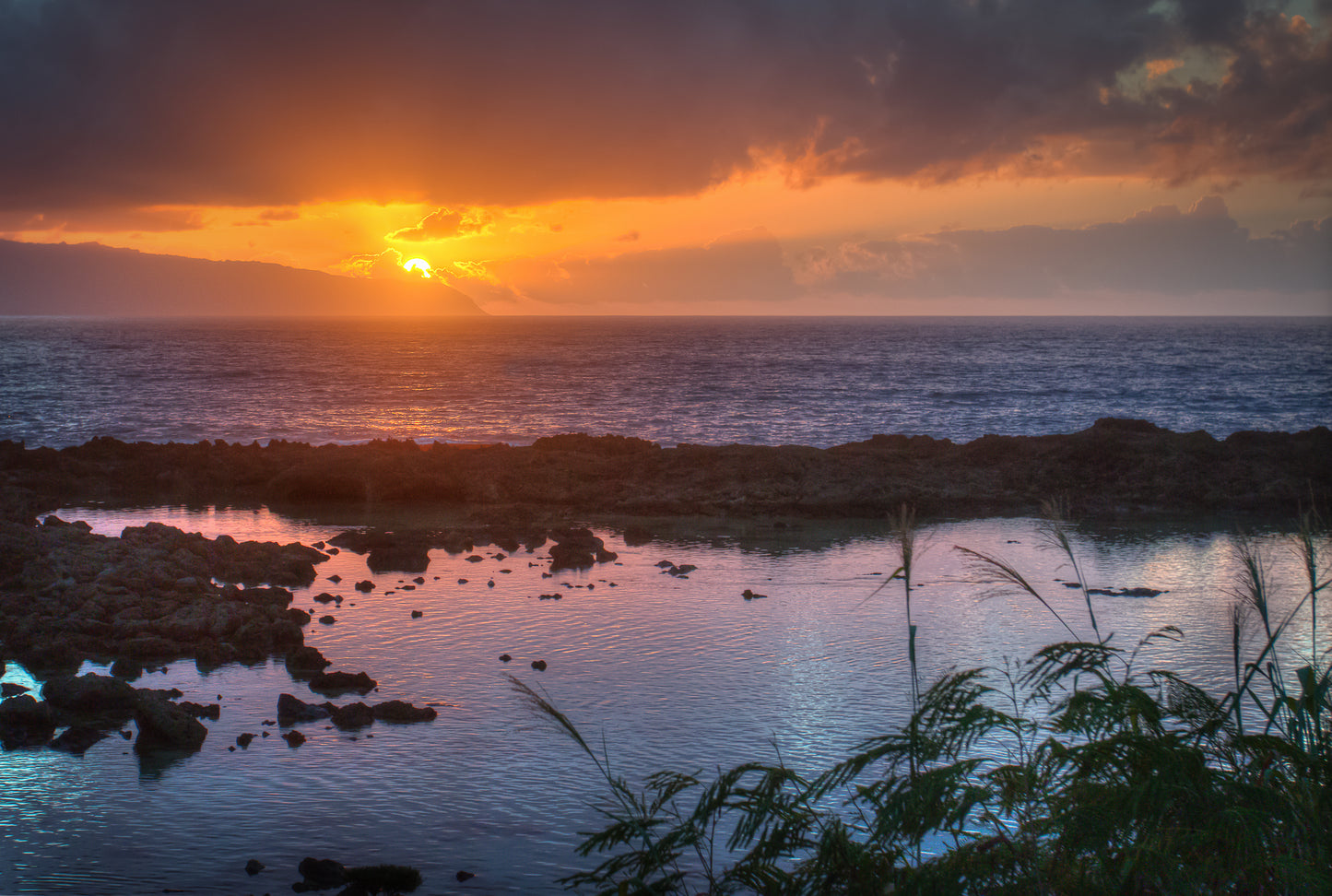 s A purple and gold vibrant sunset looking across Shark's Cove on Oahu
